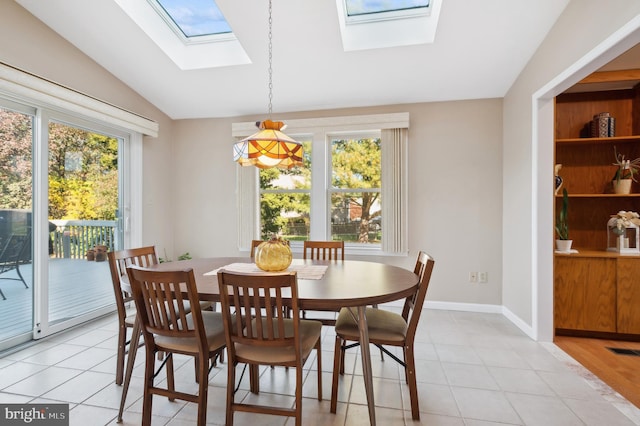 tiled dining space with vaulted ceiling with skylight and a healthy amount of sunlight