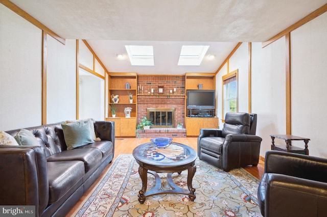 living room with light hardwood / wood-style floors, a fireplace, vaulted ceiling with skylight, and built in shelves