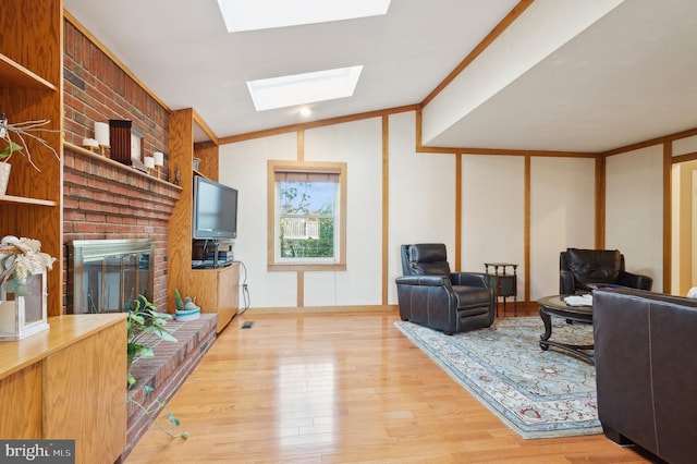 living room featuring hardwood / wood-style floors, lofted ceiling with skylight, and a brick fireplace