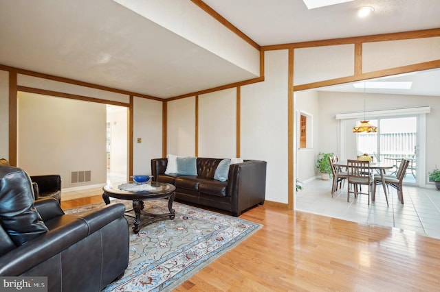 living room with hardwood / wood-style flooring and vaulted ceiling with skylight