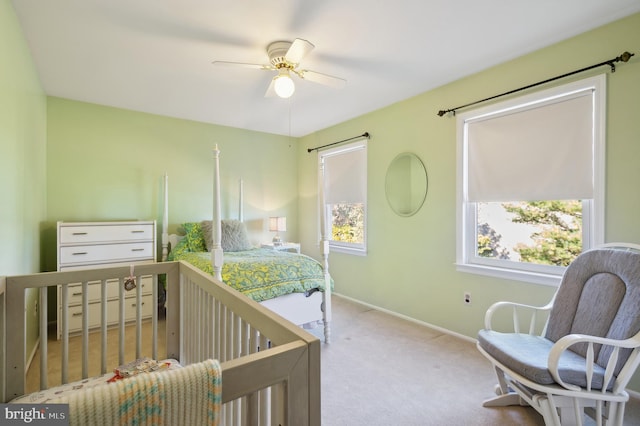 carpeted bedroom with a nursery area and ceiling fan