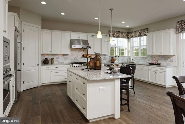 kitchen featuring backsplash, hanging light fixtures, a kitchen island, dark hardwood / wood-style flooring, and white cabinetry