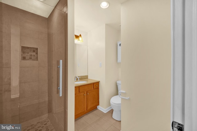 bathroom with vanity, tile patterned flooring, toilet, and a tile shower