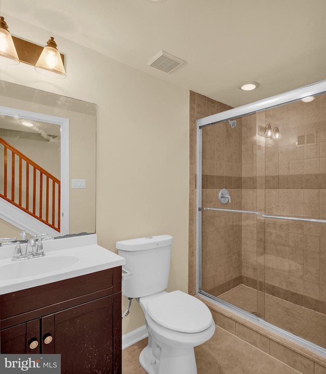 bathroom with tile patterned flooring, vanity, toilet, and a shower with shower door