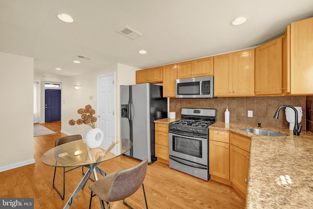 kitchen with stainless steel appliances, light hardwood / wood-style floors, sink, backsplash, and light stone countertops