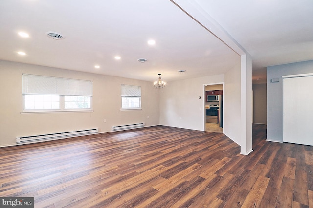 spare room featuring a chandelier, dark hardwood / wood-style flooring, and a baseboard heating unit