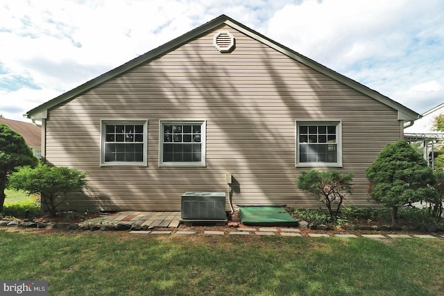 view of side of property featuring central AC and a lawn