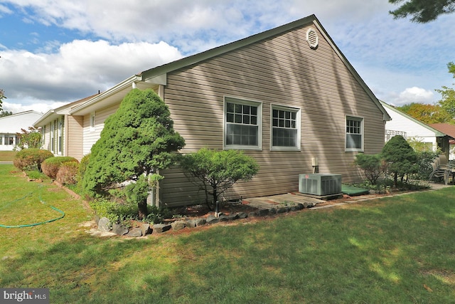 view of side of home with a yard and central AC