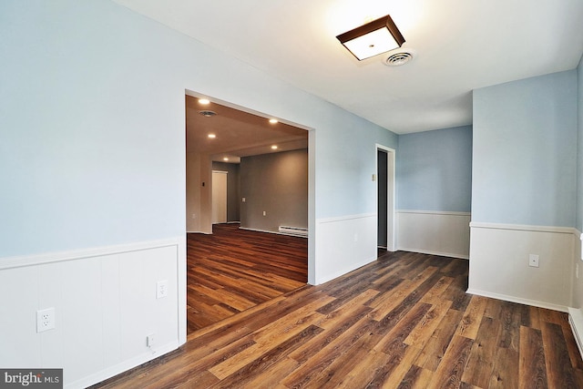 unfurnished room with dark hardwood / wood-style floors and a baseboard heating unit