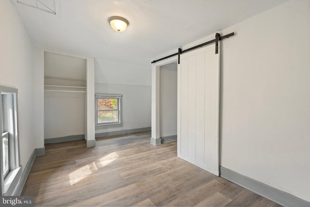 unfurnished bedroom with light hardwood / wood-style floors, a closet, and a barn door