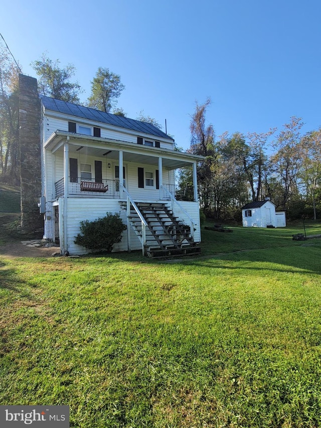 view of front of property featuring covered porch, a storage unit, and a front lawn