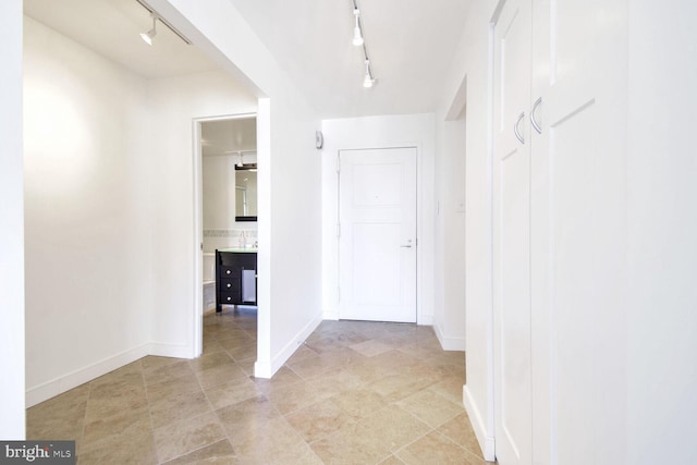 hall with rail lighting and light tile patterned floors