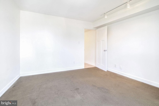 carpeted spare room with track lighting