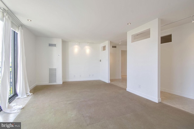 unfurnished room with light colored carpet and rail lighting