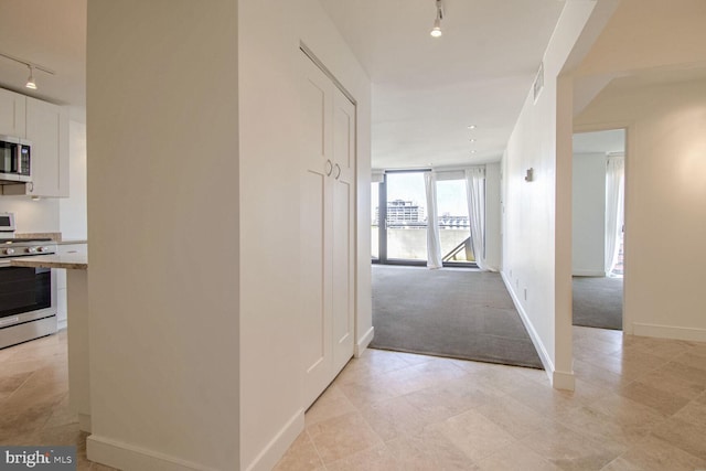 hallway featuring track lighting and light colored carpet