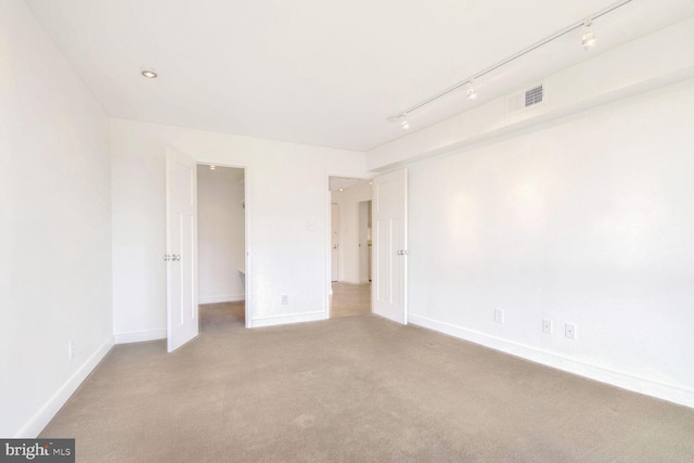 empty room with light carpet and track lighting