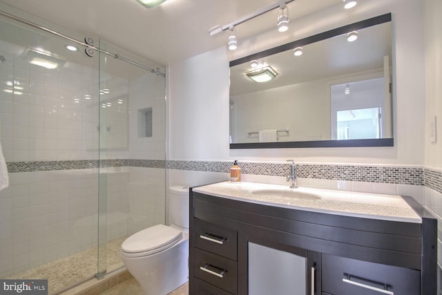 bathroom with vanity, toilet, tile walls, and a shower with door