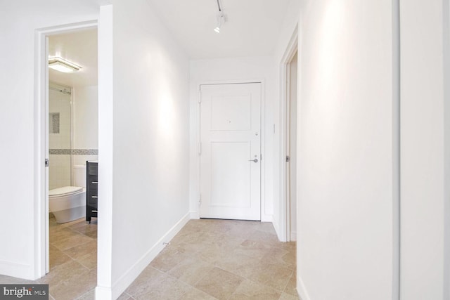 corridor featuring rail lighting and light tile patterned floors