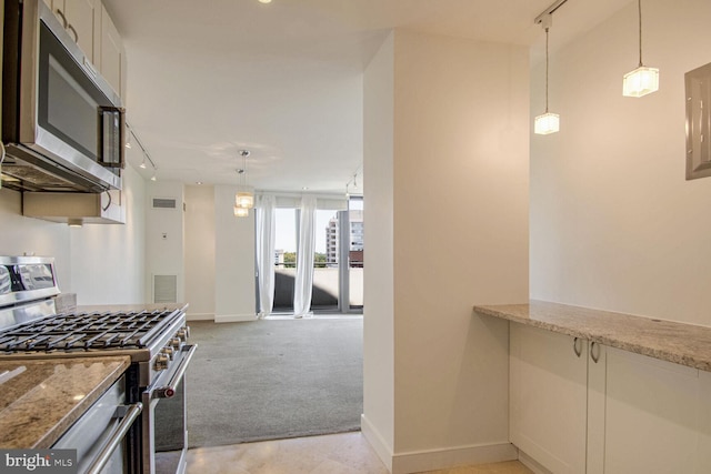 kitchen featuring light stone countertops, hanging light fixtures, stainless steel appliances, and white cabinets