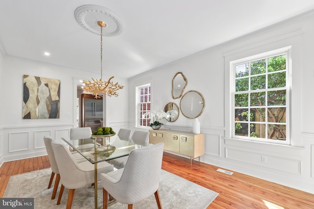 dining area with a chandelier, crown molding, and hardwood / wood-style flooring