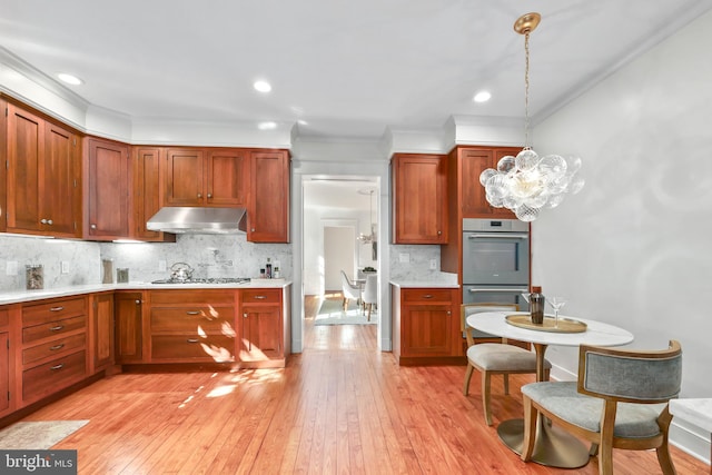 kitchen featuring stainless steel appliances, pendant lighting, light hardwood / wood-style floors, and tasteful backsplash