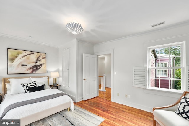 bedroom featuring crown molding and light hardwood / wood-style flooring