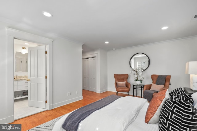 bedroom featuring a closet, connected bathroom, light wood-type flooring, and crown molding