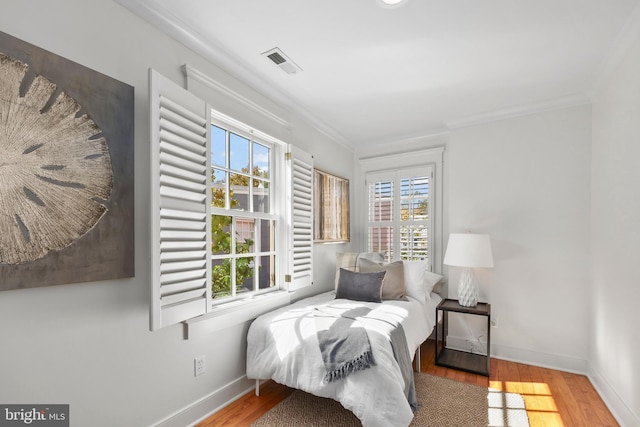 bedroom with ornamental molding and hardwood / wood-style flooring