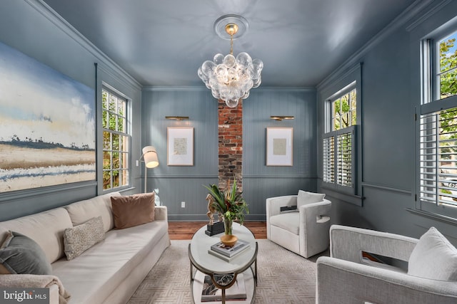 living room with light hardwood / wood-style floors, an inviting chandelier, ornamental molding, and a healthy amount of sunlight