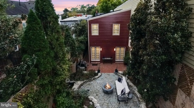 property exterior at dusk with a patio and an outdoor fire pit