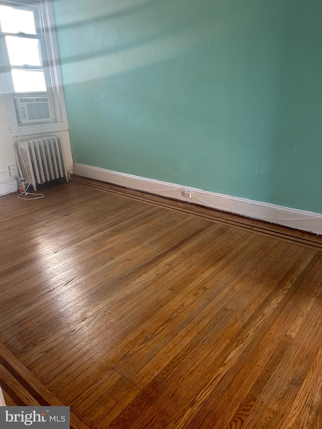 unfurnished room featuring wood-type flooring, cooling unit, and radiator