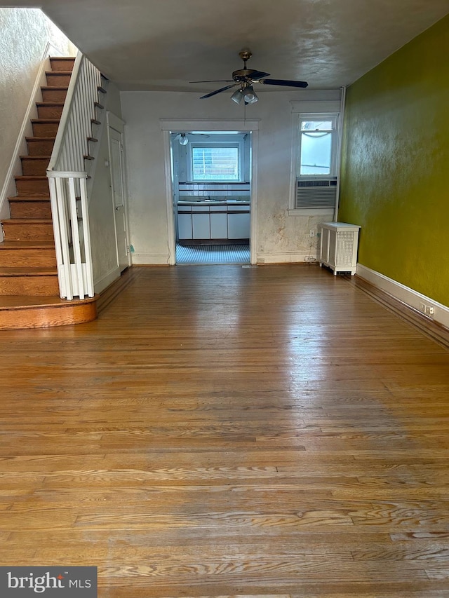 unfurnished living room featuring a wealth of natural light, radiator, and light hardwood / wood-style flooring