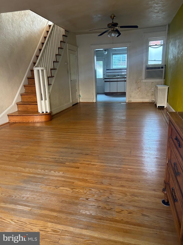 unfurnished living room with hardwood / wood-style flooring, ceiling fan, and radiator heating unit