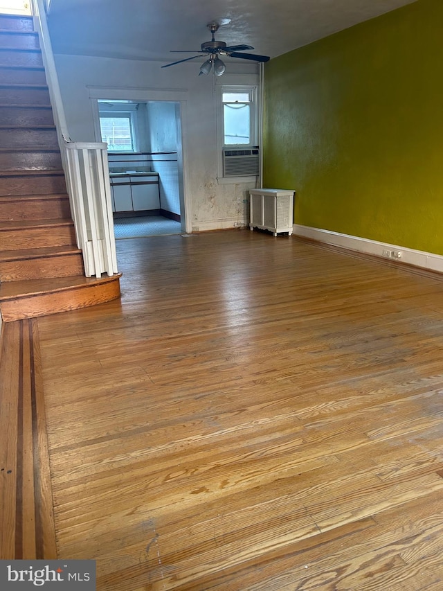 unfurnished living room featuring cooling unit, ceiling fan, radiator, and light hardwood / wood-style floors