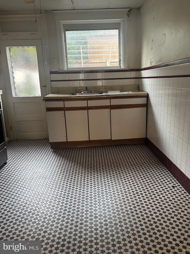 kitchen featuring white cabinetry, tile walls, and sink