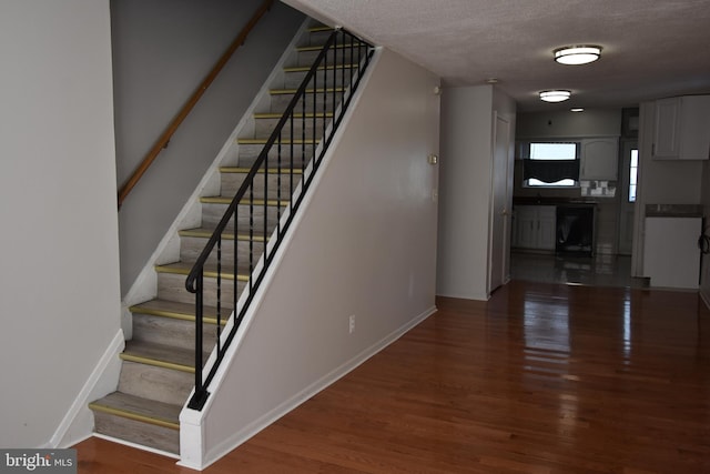 staircase featuring a textured ceiling and hardwood / wood-style flooring