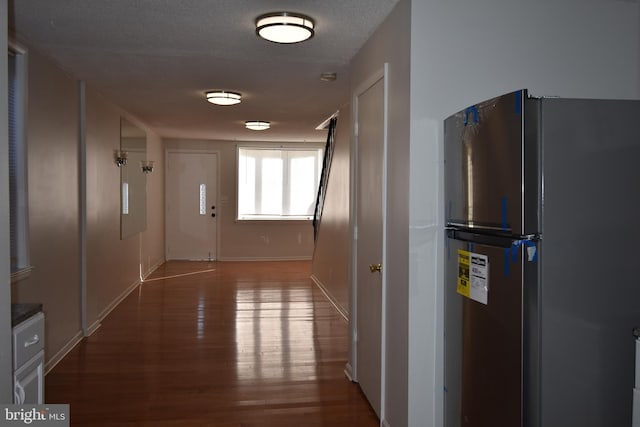 hallway with a textured ceiling and hardwood / wood-style floors