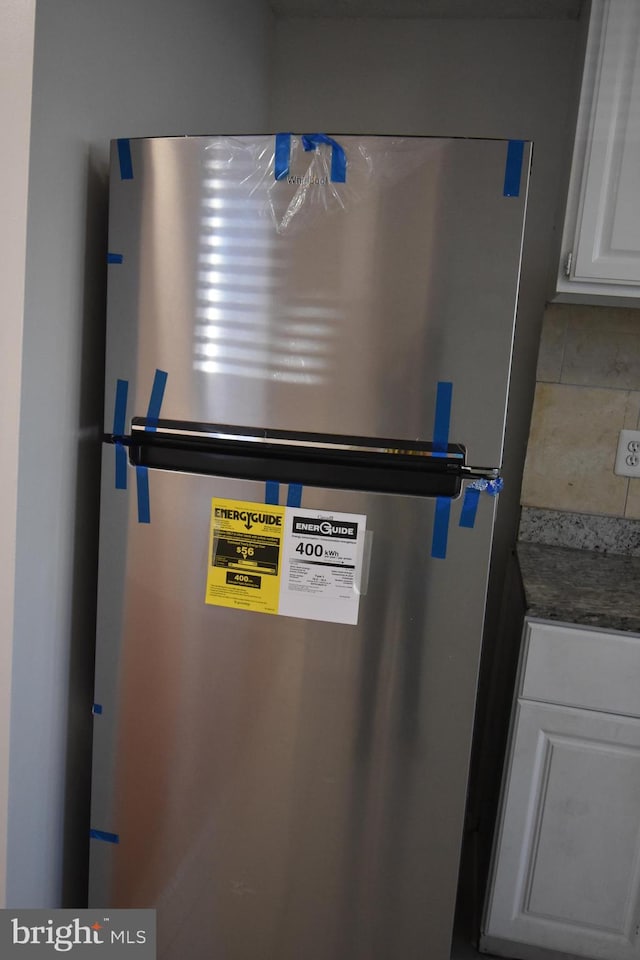 room details with tile patterned flooring and stainless steel refrigerator