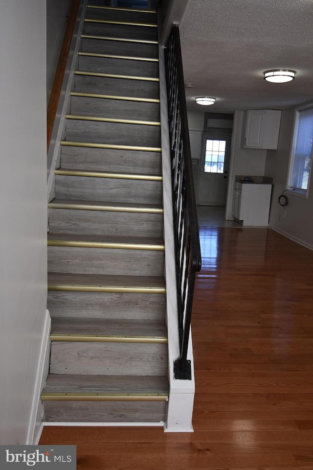 stairs with hardwood / wood-style flooring and a textured ceiling