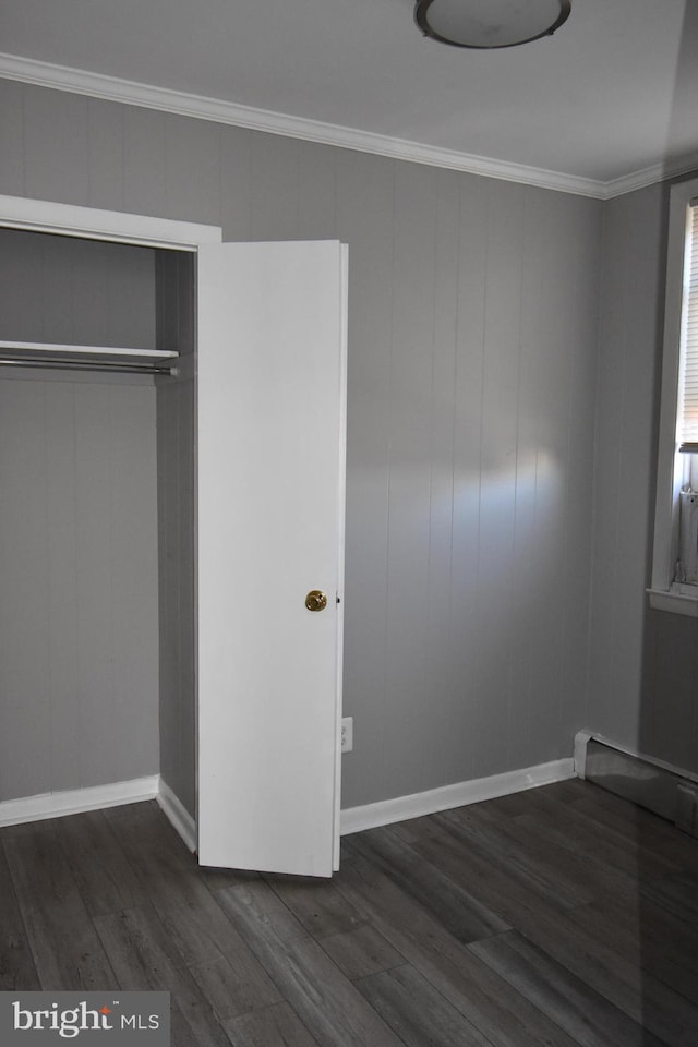 unfurnished bedroom with crown molding, dark hardwood / wood-style floors, and a closet