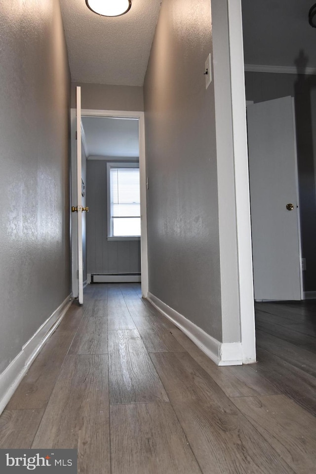 hall featuring baseboard heating, a textured ceiling, and wood-type flooring