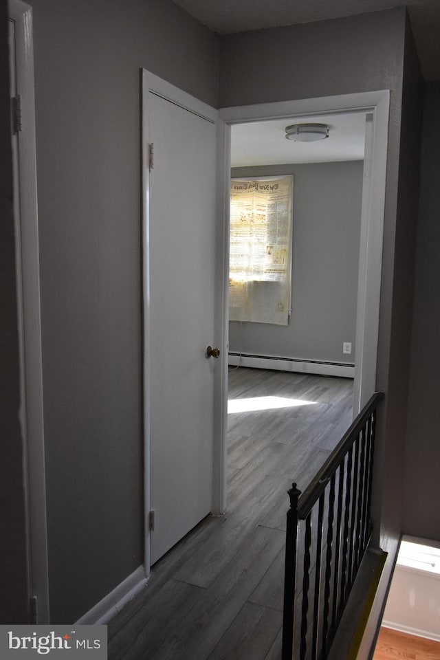 hall featuring a baseboard heating unit and hardwood / wood-style flooring