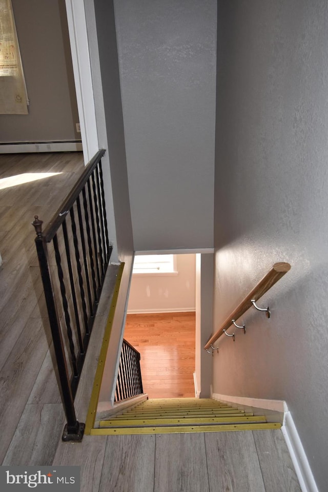 stairs featuring hardwood / wood-style flooring and baseboard heating