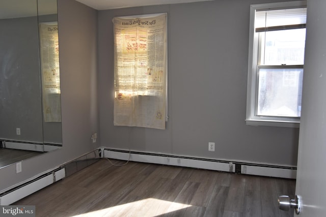 empty room with a baseboard heating unit and dark hardwood / wood-style floors