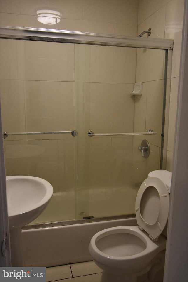 full bathroom featuring toilet, tile patterned floors, combined bath / shower with glass door, and sink