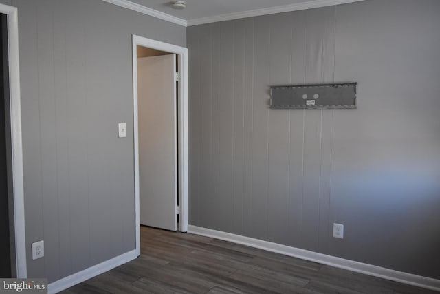 empty room with crown molding, wooden walls, and dark wood-type flooring