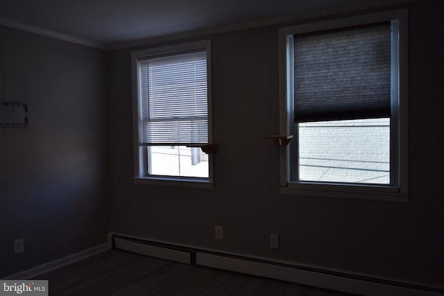 empty room featuring ornamental molding, baseboard heating, and dark hardwood / wood-style floors