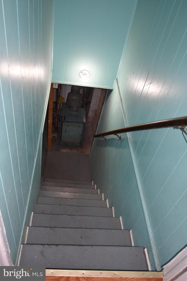 staircase with wooden walls and a wood stove