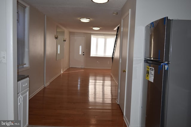 corridor with a textured ceiling and hardwood / wood-style floors