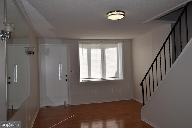 foyer entrance with hardwood / wood-style floors and a textured ceiling